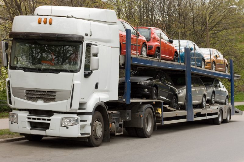Caminhão-cegonha carregado com carros, imagem ilustrativa sobre transporte de veículos.