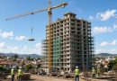 Edificio residencial em construcao com guindaste e trabalhadores em cidade brasileira - imagem ilustrativa
